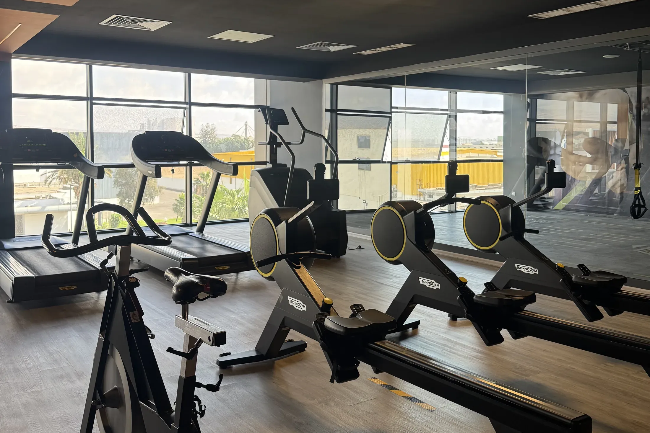 Plateau cardio : vélos et rameurs devant les baies vitrées