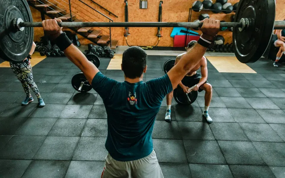 Un adhérent lève une barre chargée au-dessus de la tête dans une salle de musculation