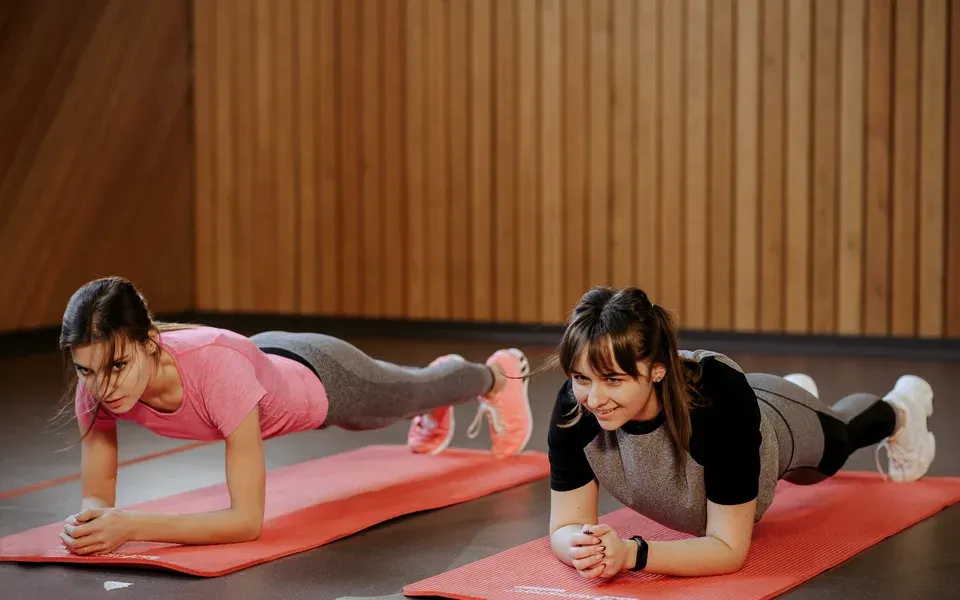 Deux femmes en position de gainage sur des tapis rouges