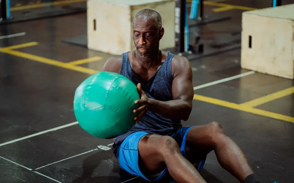 Un homme travaille avec un médecine-ball vert assis au sol