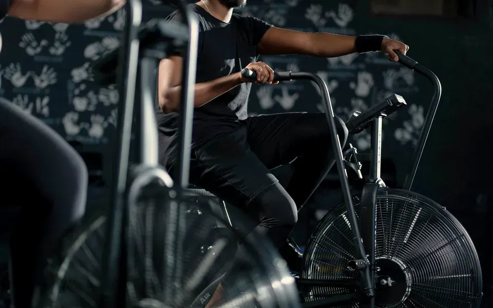 Un adepte pédale sur un vélo à air devant un mur noir