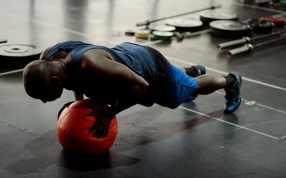 Un homme en pompes sur un médecine-ball orange