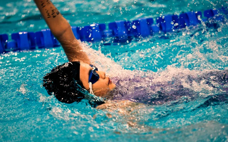 Une nageuse en dos crawlé dans une piscine