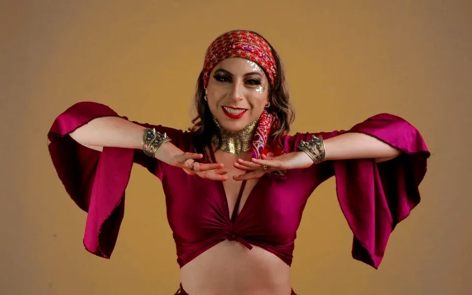 Une danseuse orientale en tenue pourpre sur fond orange