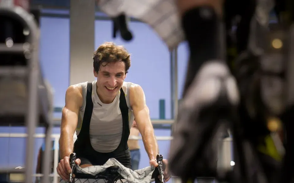 Un cycliste souriant pédale sur un vélo en salle