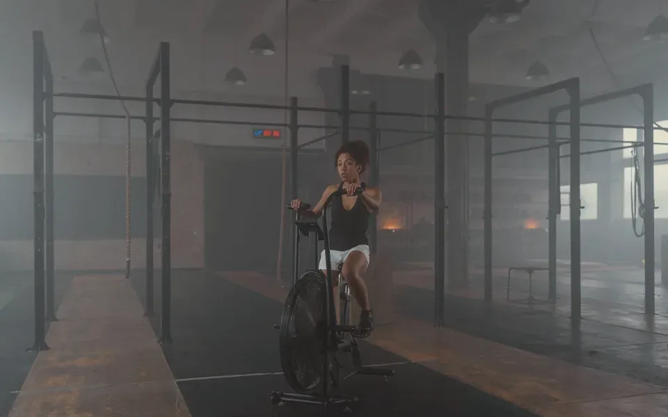 Une femme pédale sur un vélo à air dans une grande salle brumeuse