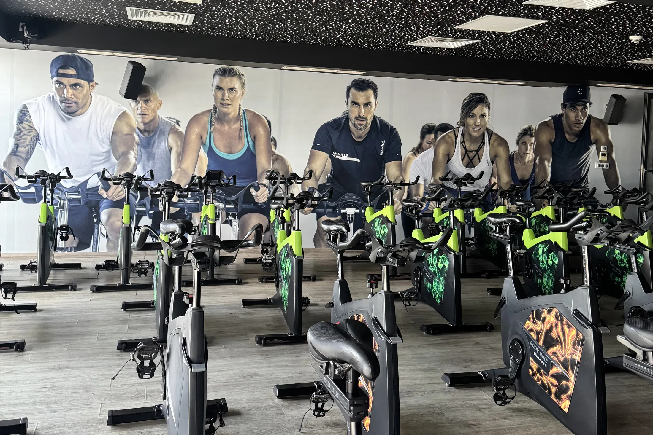 Studio RPM : rangées de vélos face à une fresque de cyclistes