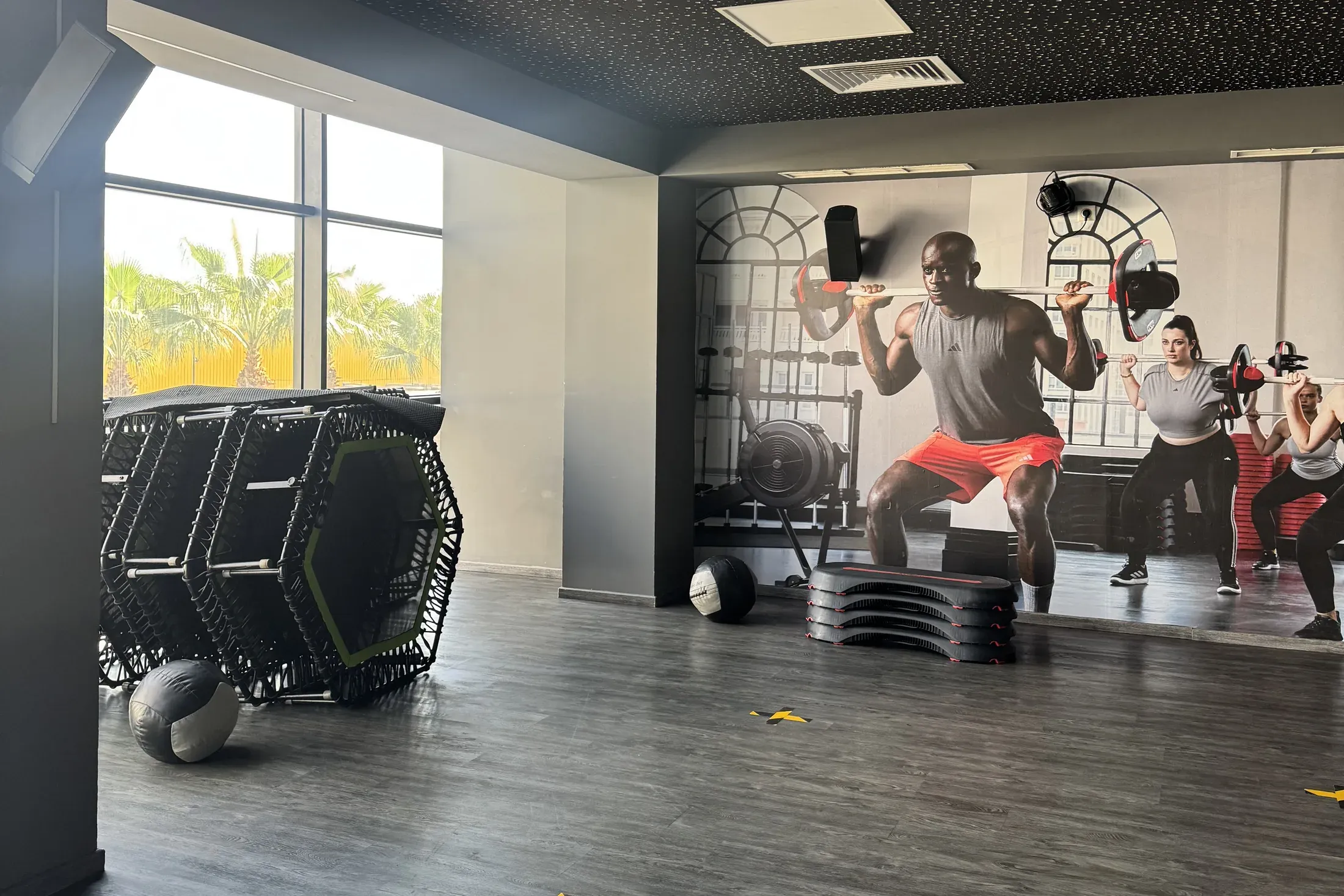 Elite Studio : grande salle de cours avec baies vitrées, trampolines et fresque d’athlètes